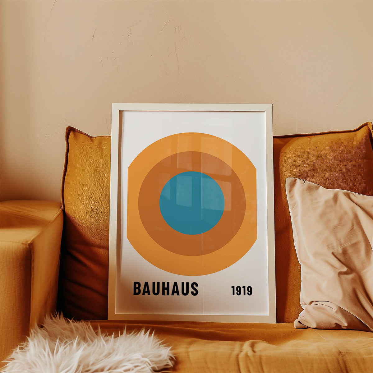 Framed Bauhaus Circle Poster leaning on a mustard sofa with cushions in warm colours