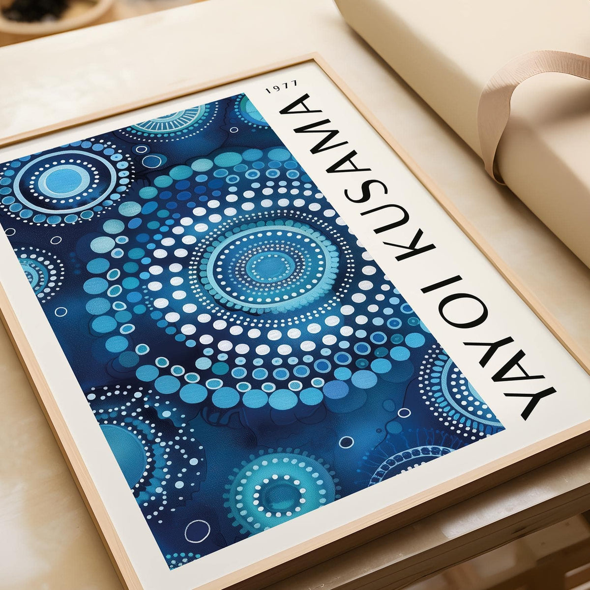 Close-up of Mandala wall art with blue circular dot pattern and wooden frame on a table with brown ribbon