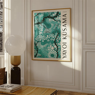 Print on a wall of abstract branches and dots in teal and black above a wooden table lamp