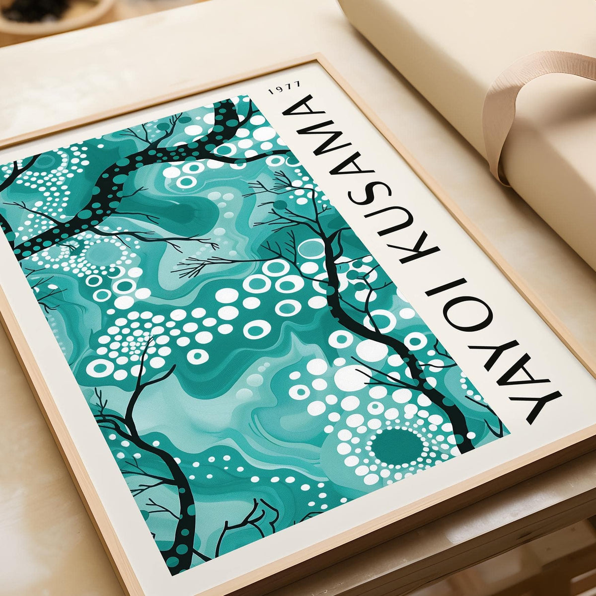 Teal wall decor with abstract branches and white dots close-up on a wooden surface near a wrapped gift