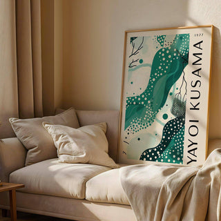 Black White and Green Poster leaning on a sofa with cushions and a beige throw in natural light