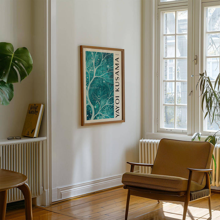 Teal Color Wall Art with abstract teal branches hanging on a white wall above a tan armchair