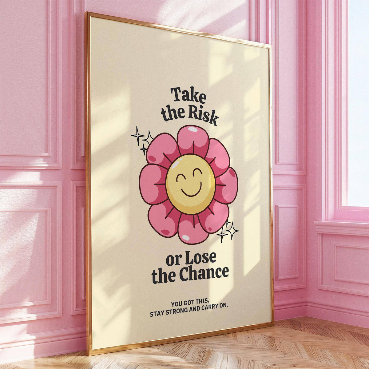 Framed Motivational Quotes wall art with a smiling flower and pink petals leaning on a wooden floor with a pink wall