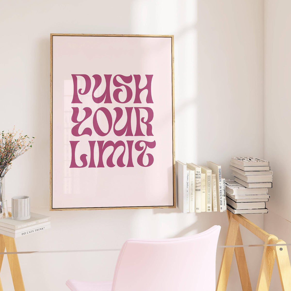 Quote motivational posters in a wooden frame with purple text on pale pink above a glass desk with books and a chair