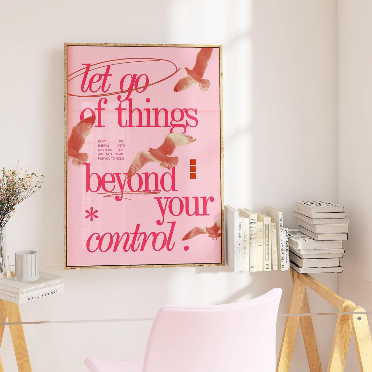 Posters with Inspirational Sayings framed print in pink and red on a white wall next to a clear desk with books and a pink chair