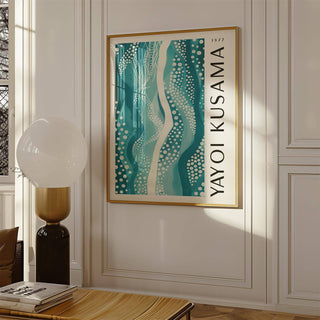 Abstract Picture wall art in teal with dotted patterns in a gold frame above a wooden table with a modern lamp