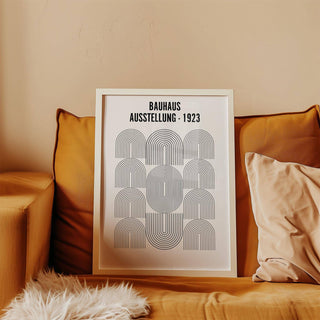 Framed Bauhaus Minimalism Art with black line arches resting on a mustard yellow sofa with cushions