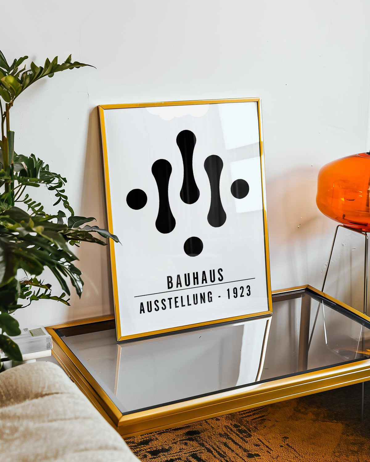 Framed Bauhaus Art Black and White print with abstract black shapes leaning on a glass table near a green plant