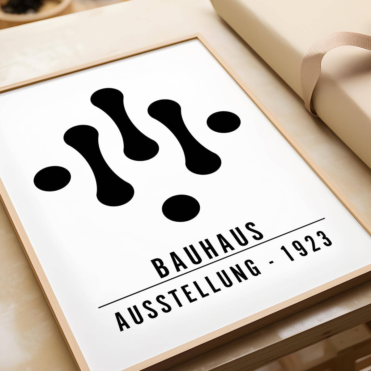Close-up of Bauhaus Art Black and White print with abstract shapes and text leaning near cream wrapping