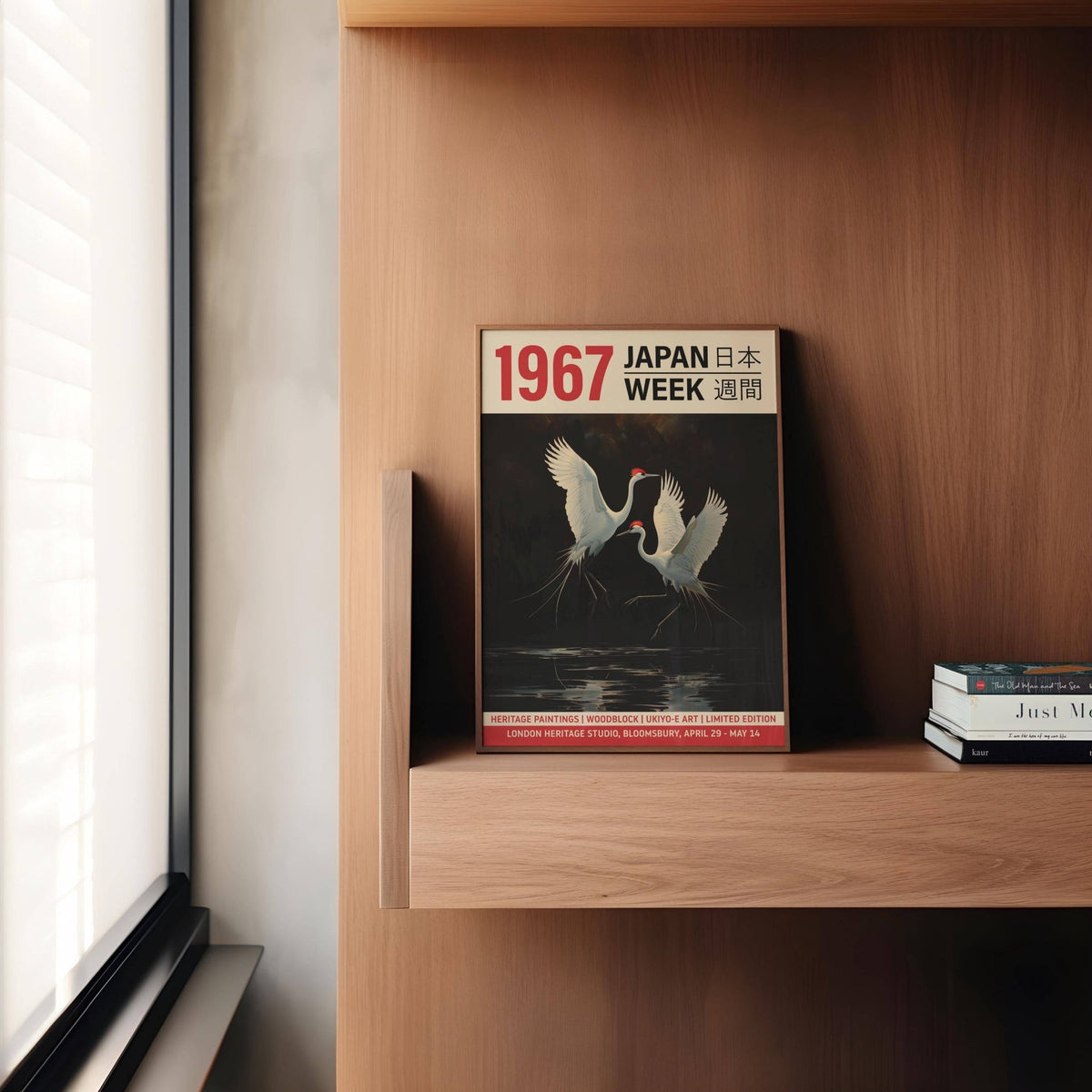 Crane art print leaning on a wooden shelf with books nearby in natural light