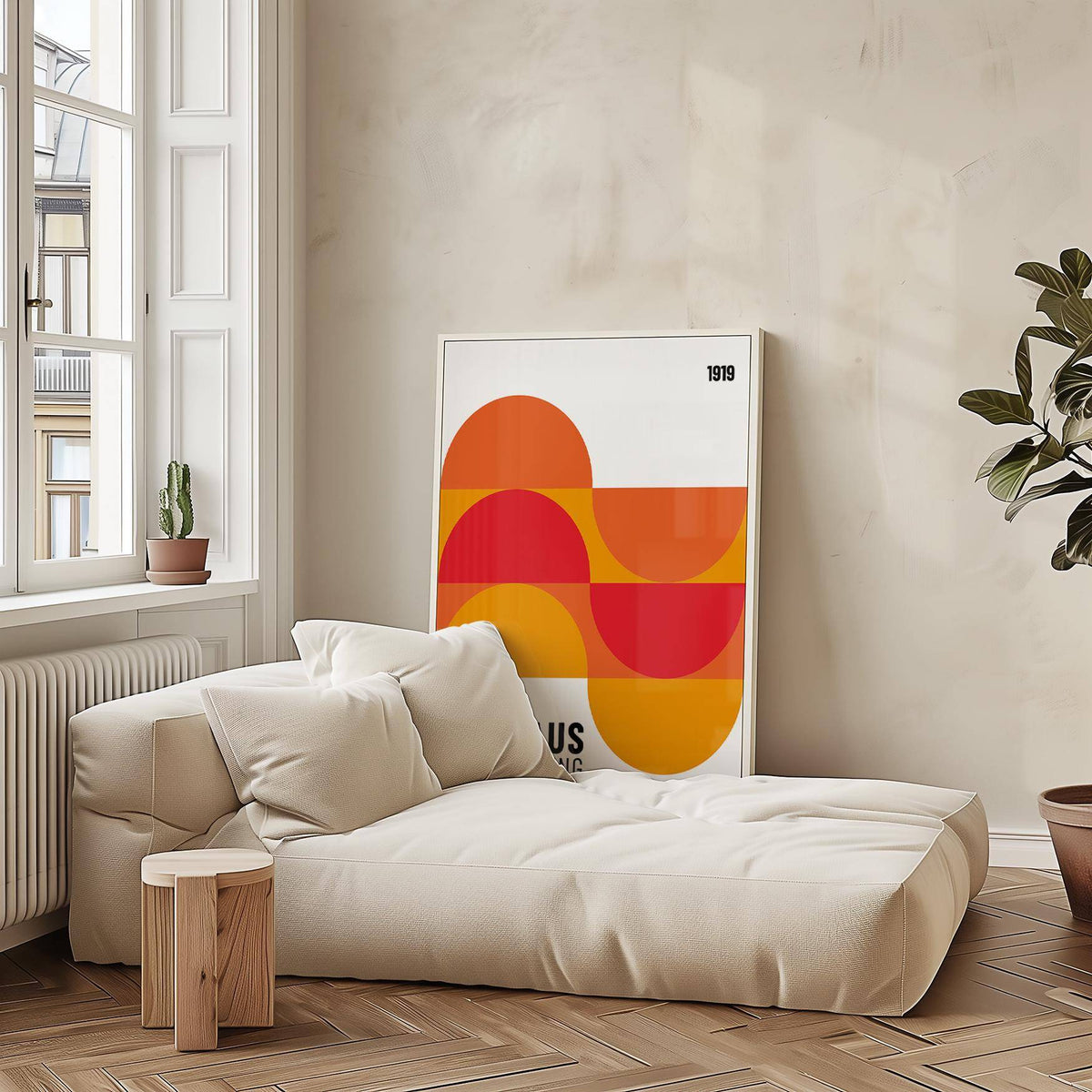 Print leaning on a neutral lounge beside a green potted plant with orange and red geometric shapes
