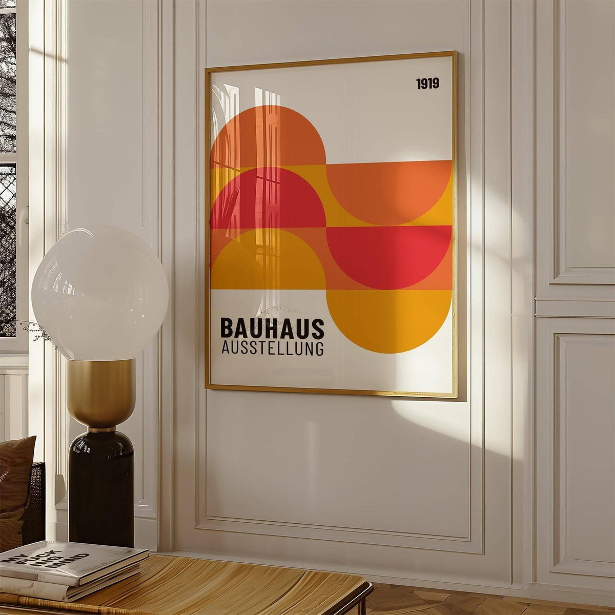 Inexpensive artwork framed print of abstract geometric shapes in orange and red hung on a white wall with a lamp nearby