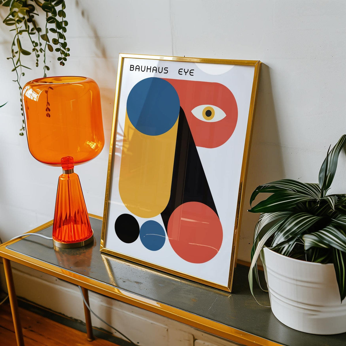 Framed Bauhaus Graphic print with blue, orange and black geometric shapes on a table next to an orange lamp