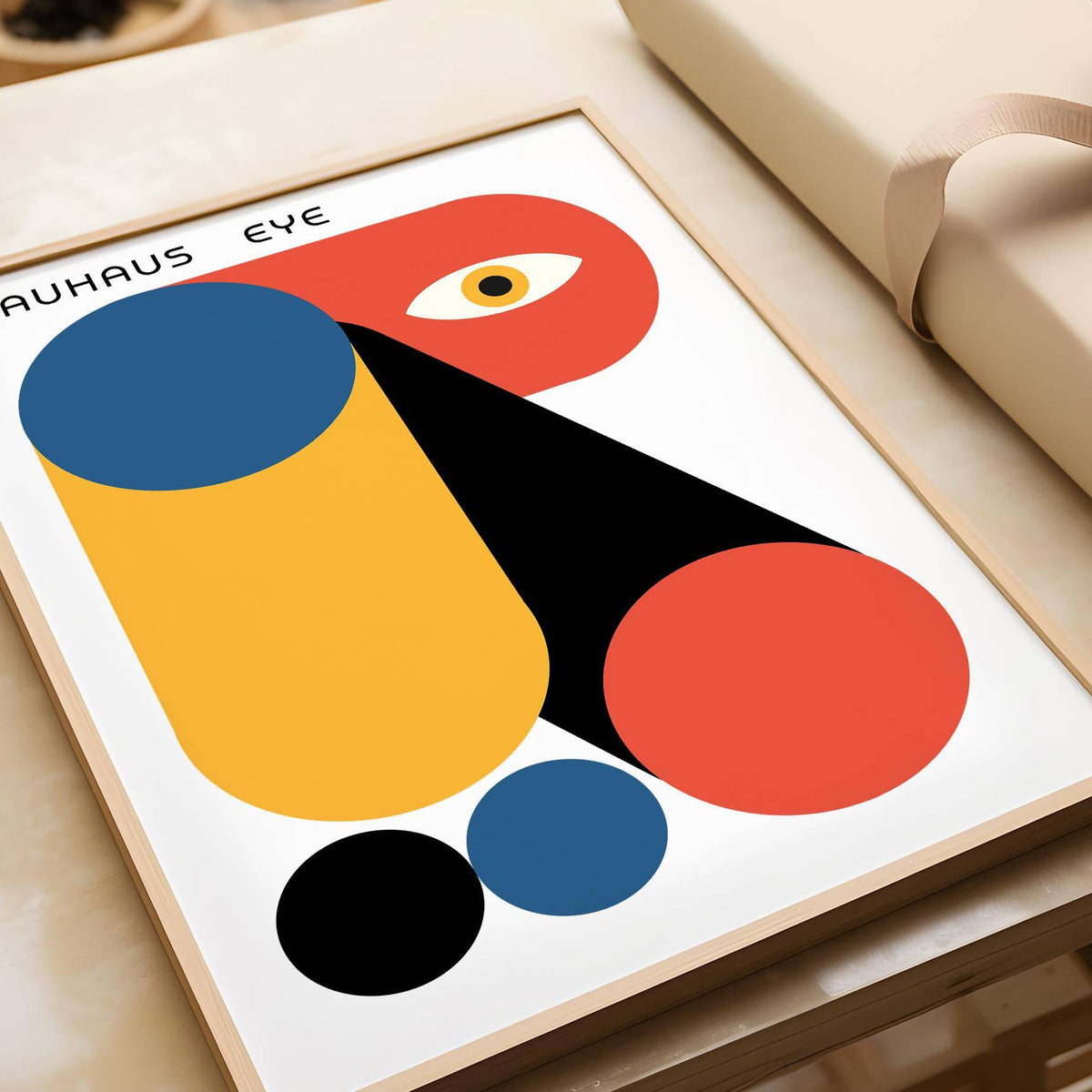 Framed Bauhaus Graphic with abstract geometric shapes in blue, orange and black leaning on a table