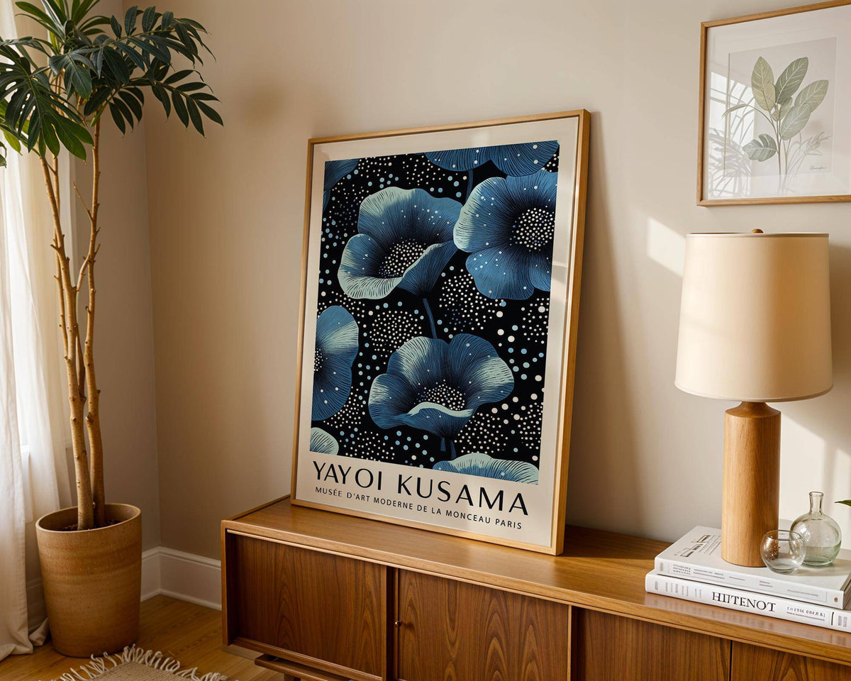 Wall Art Blue Flowers print leaning on a wooden sideboard beside a tall plant and lamp