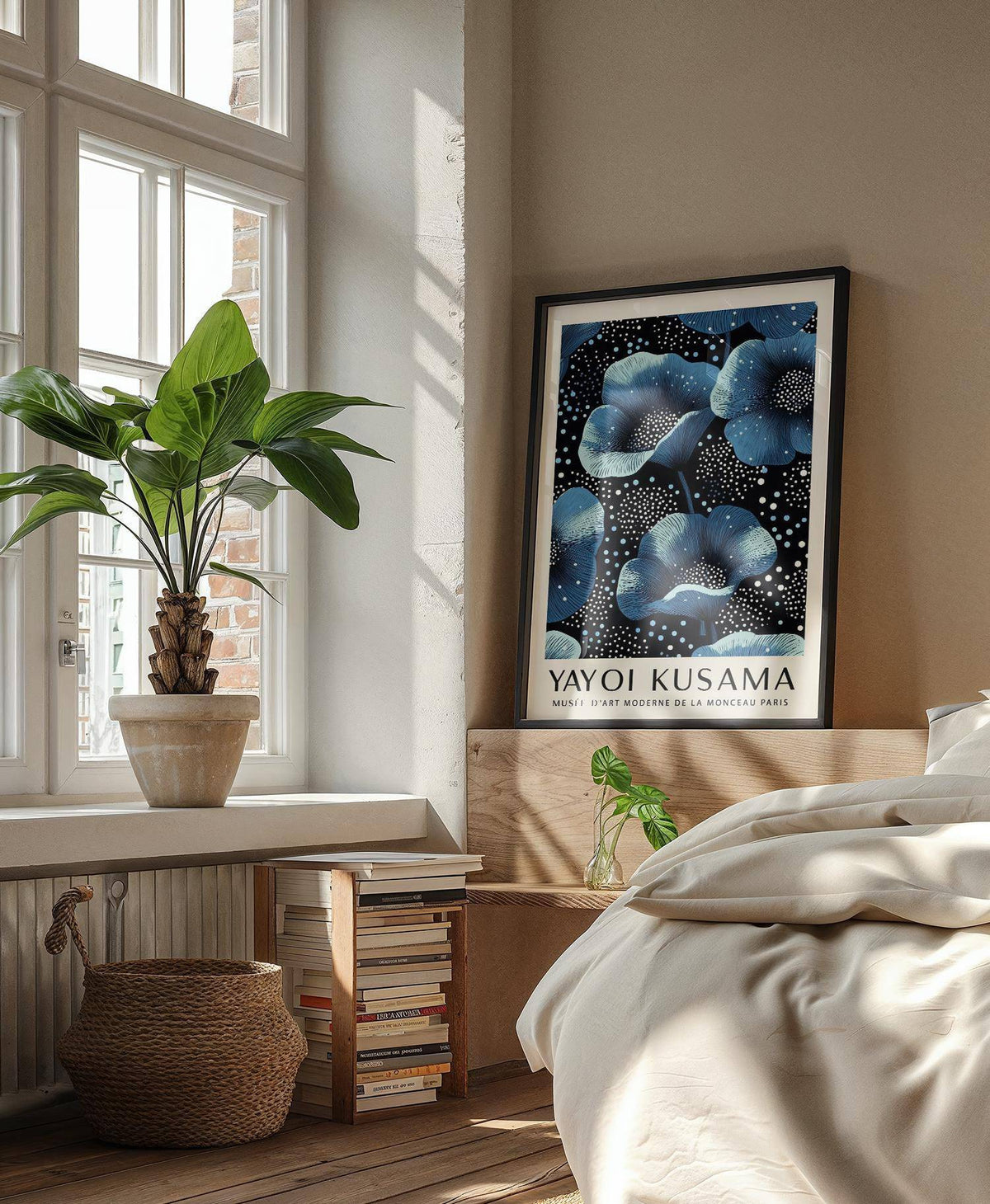 Print of wall art blue flowers with blue and black illustration leaning on bedroom headboard with a small plant
