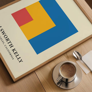 Framed close-up of modern minimal wall art with colourful nested squares beside a cup of coffee
