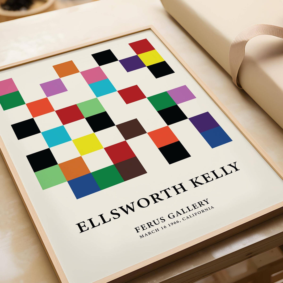 Framed close-up of colourful squares grid with text below on a wooden surface near ribbon