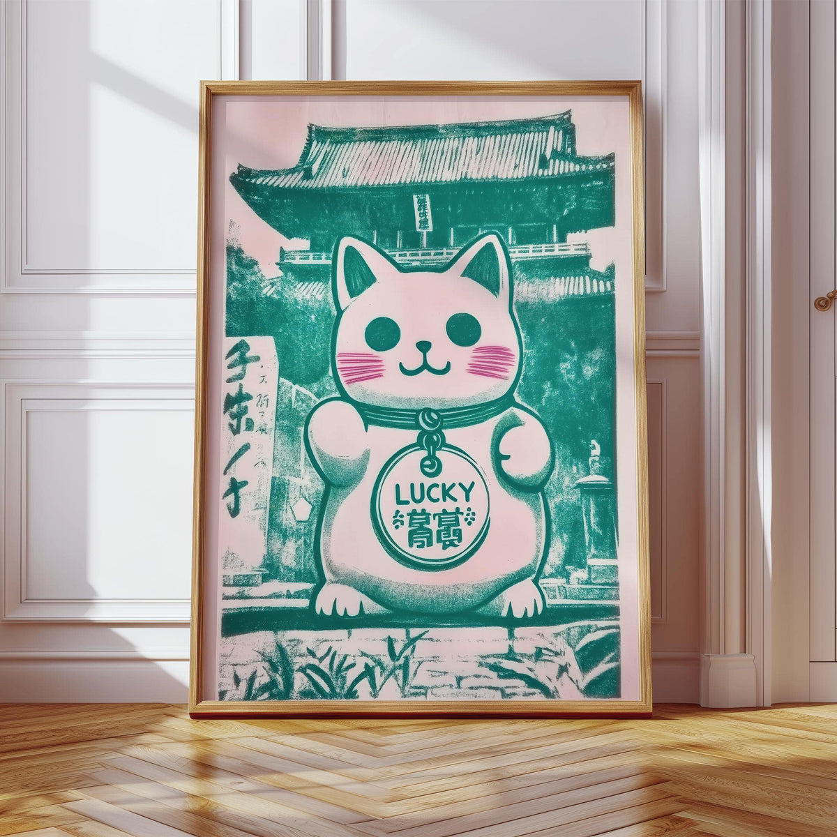 Print leaning on a floor with parquet of Good Luck Presents wall art featuring a green and pink maneki-neko cat figurine