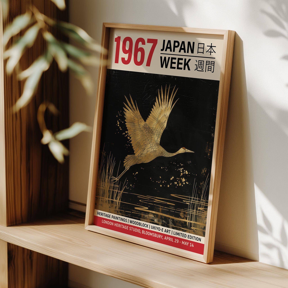Framed Large Crane Wall Art with gold crane and red text leaning on a wooden shelf