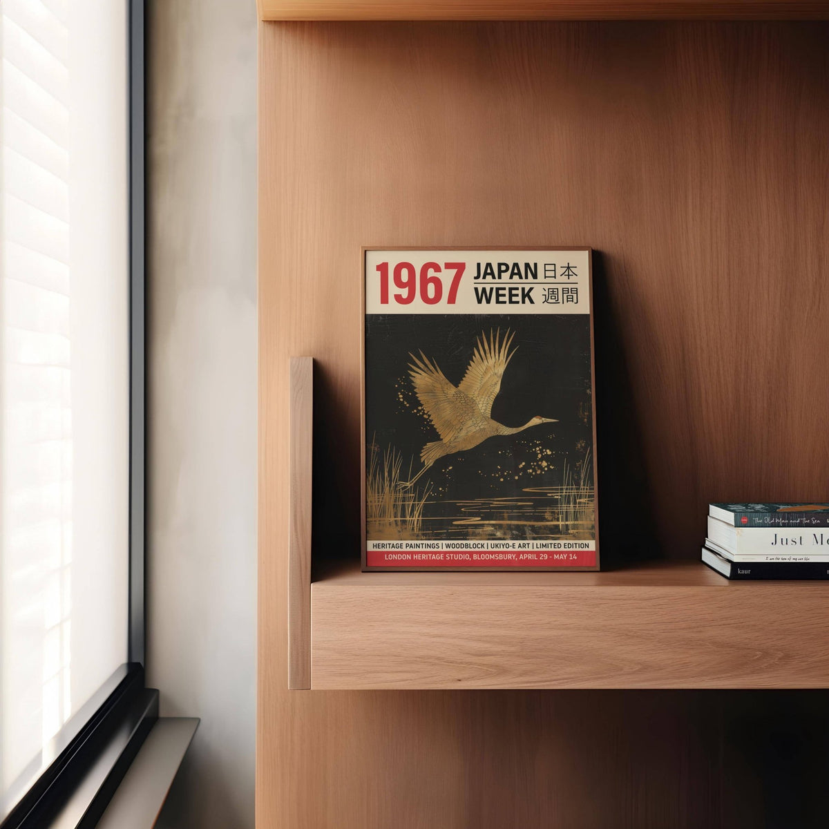 Large Crane wall art leaning on a wooden shelf with books nearby in natural light
