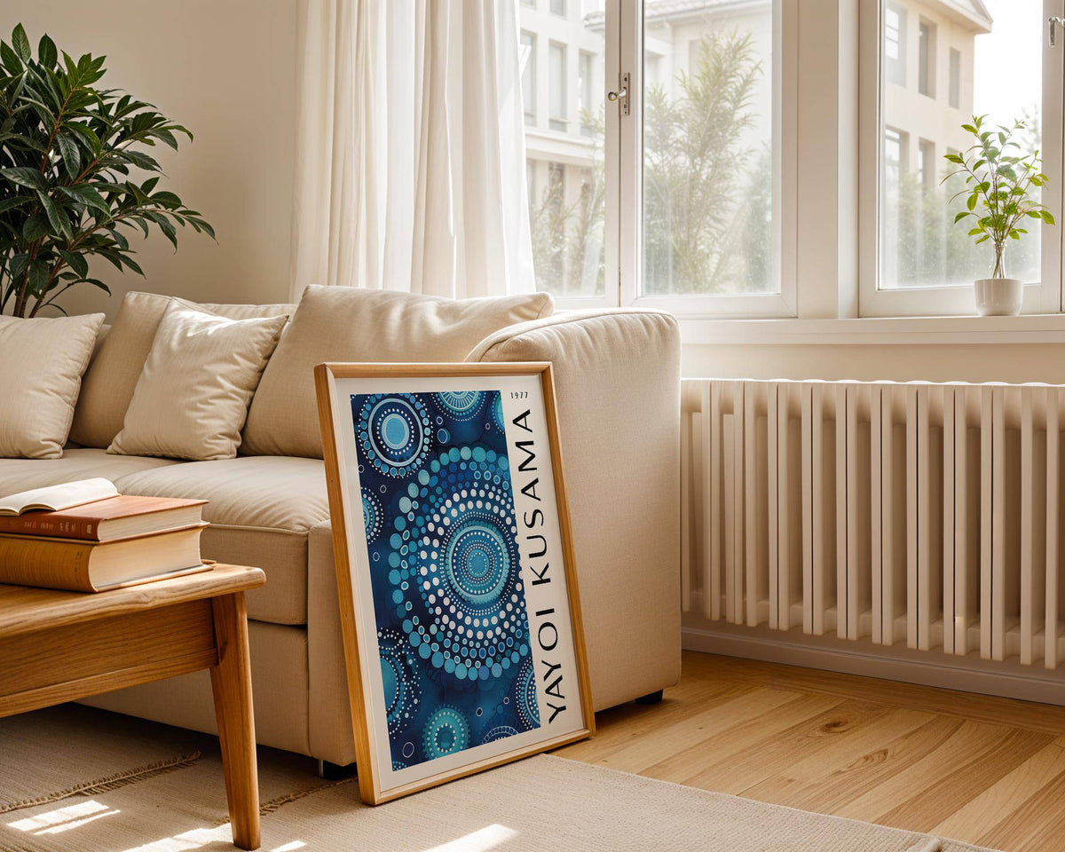 Framed mandala wall art featuring blue circular dot patterns leaning against a sofa with books on a wooden table