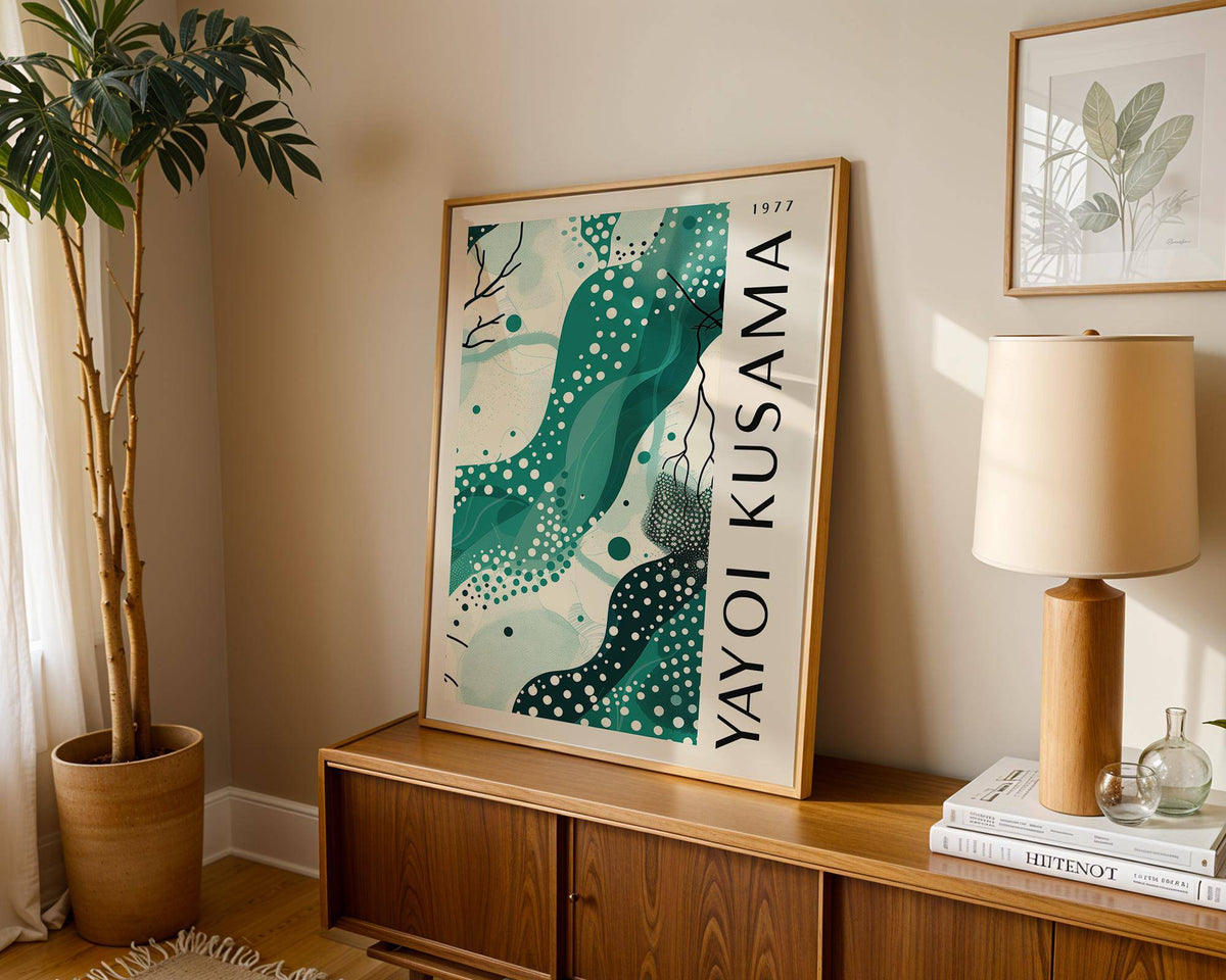 Black White and Green Poster leaning on a sideboard with a table lamp and plant nearby in a living room
