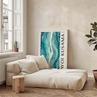 Abstract picture depicting a teal and cream abstract pattern leaning against a wall near a beige sofa and a plant