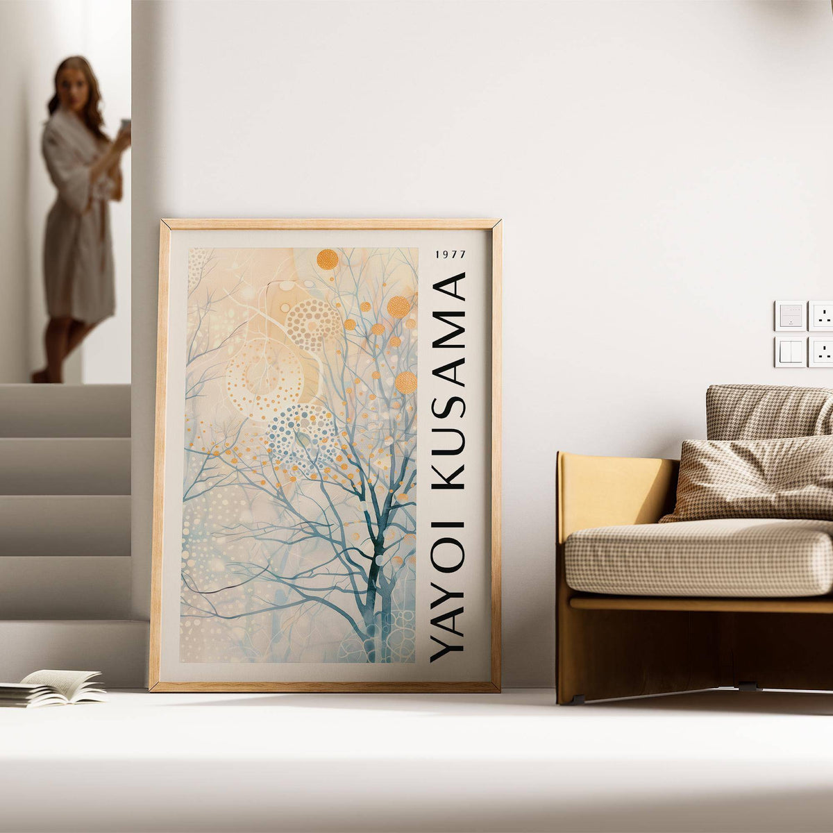 Sitting room art leaning against a wall with light abstract tree in blue and orange next to a beige checked sofa