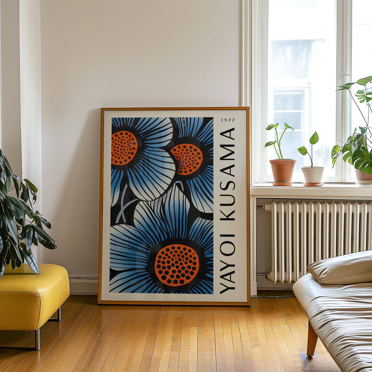 Blue living room wall art leaning on the floor near a yellow seat and plants by a window