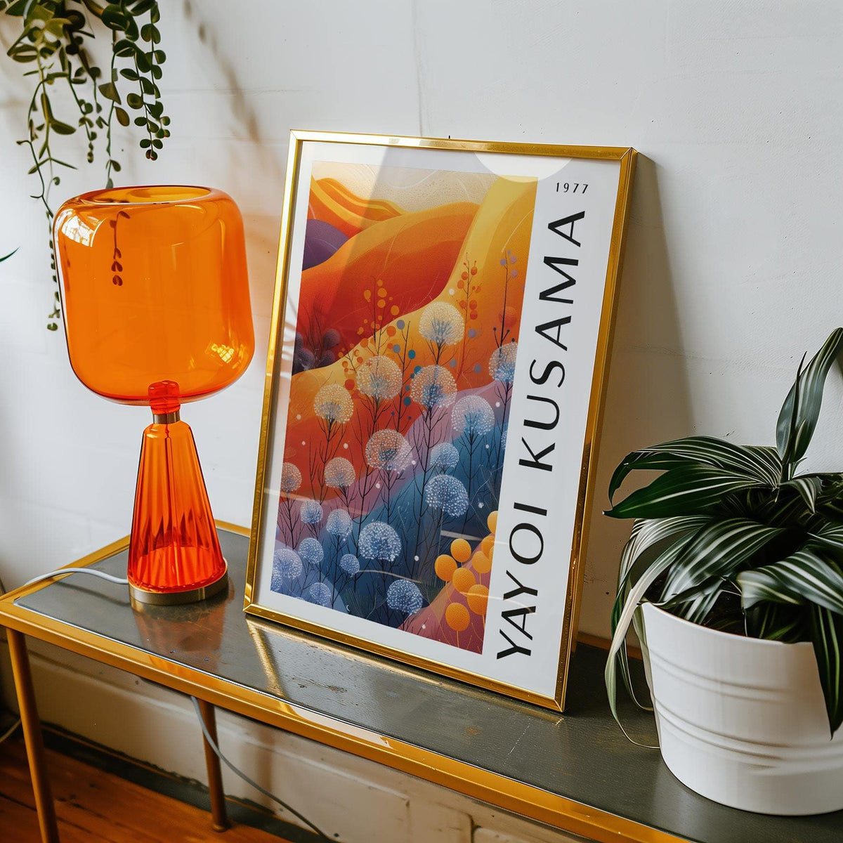 Framed print of abstract floral shapes in blue and orange leaning on a table with an orange lamp