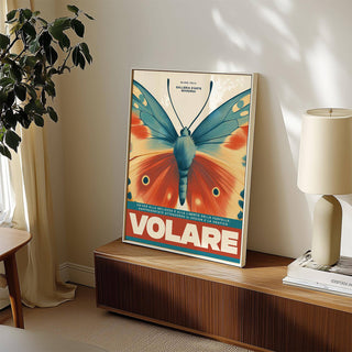 Framed print of a vintage butterfly wall art with blue and orange wings leaning on a wooden sideboard with a white lamp