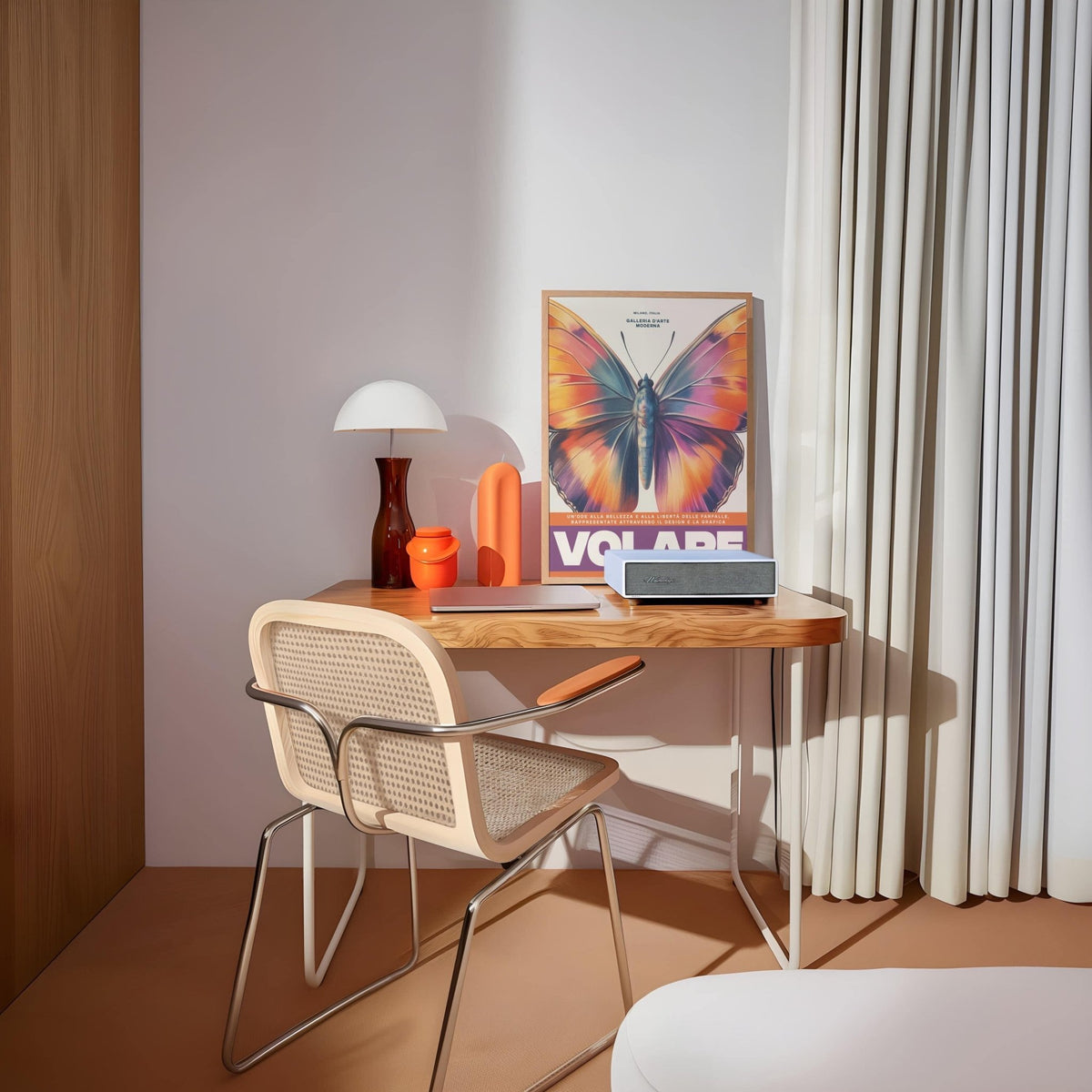 Large Butterfly Print leaning on a desk with orange and purple tones beside a lamp and curtains