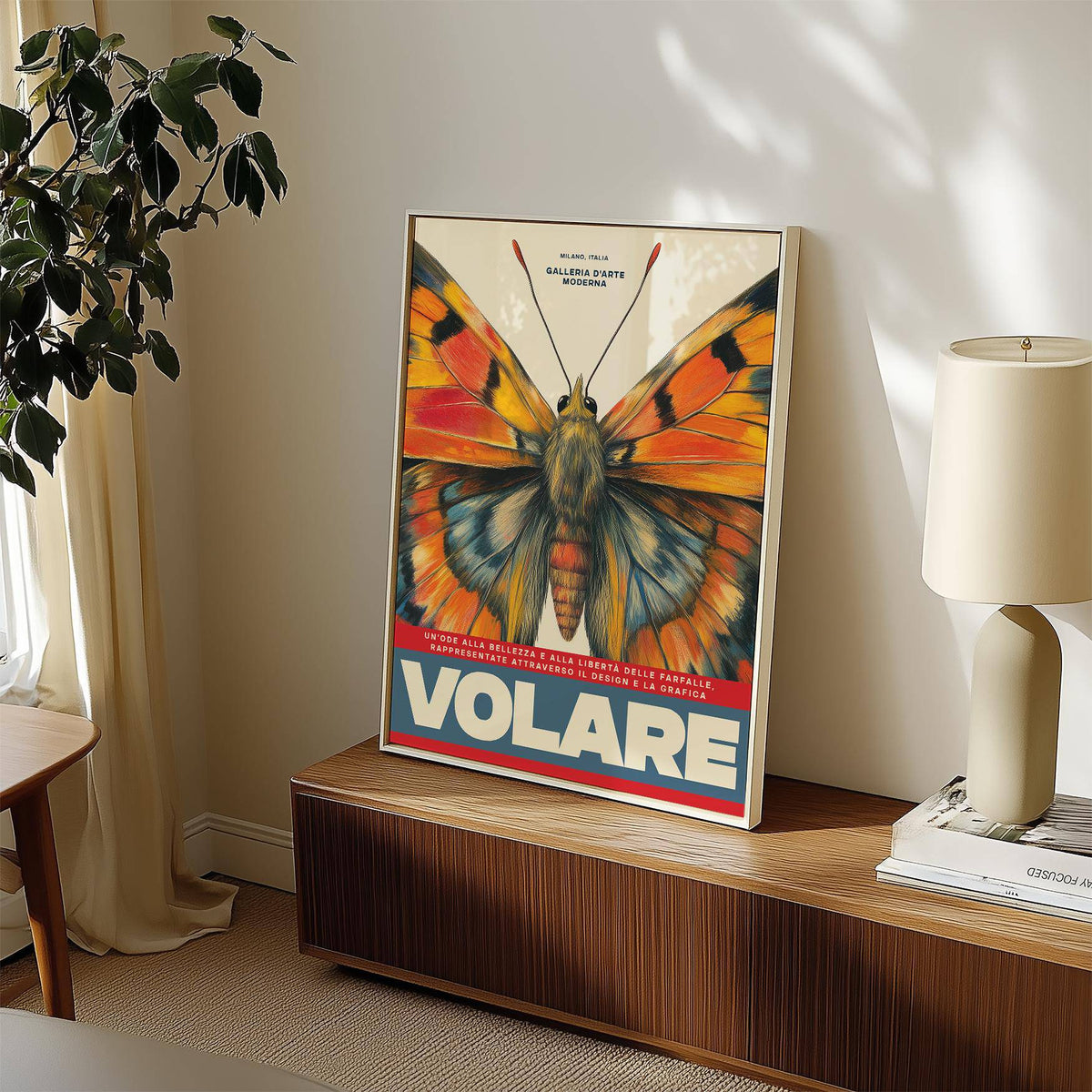Print leaning on a cabinet of butterfly art wall illustration with orange and blue wings beside a lamp