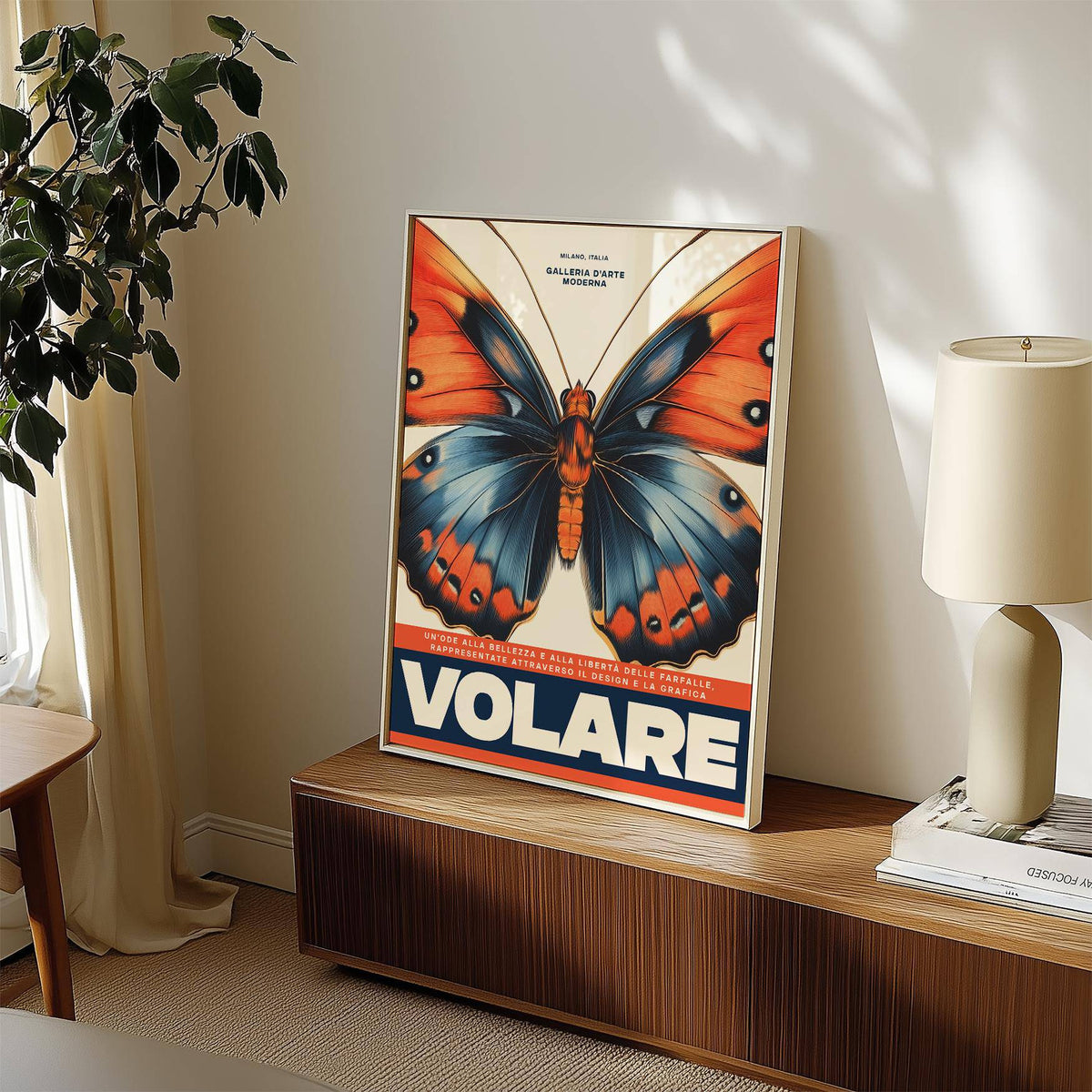 Print leaning on a cabinet of an orange and blue butterfly with bold typography and a lamp