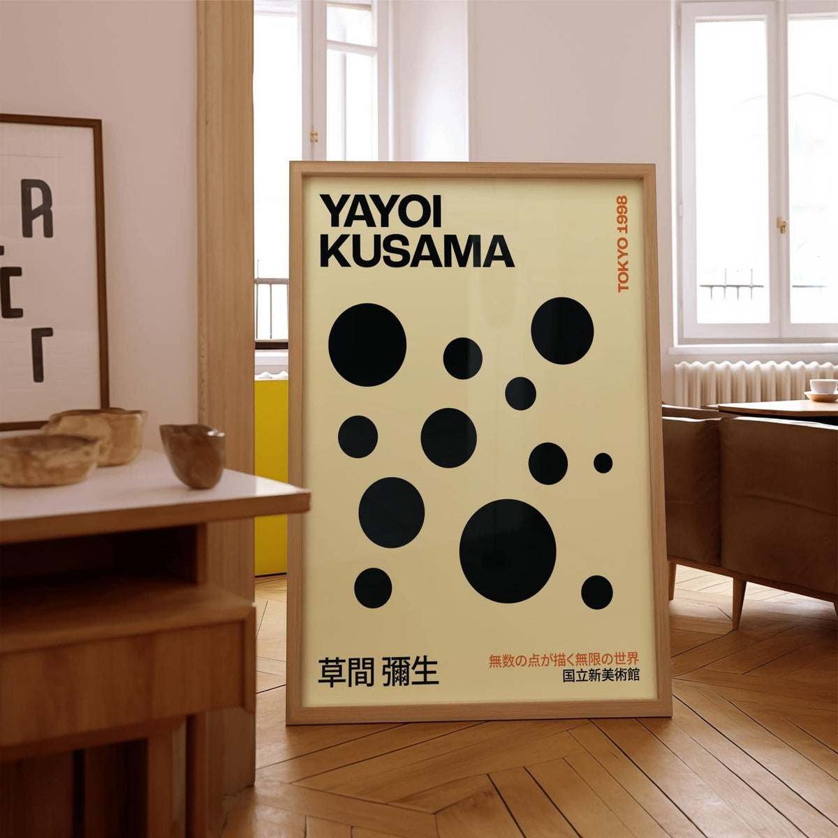 Polka Dot Artwork print with black dots on cream background leaning on the floor by a wooden shelf