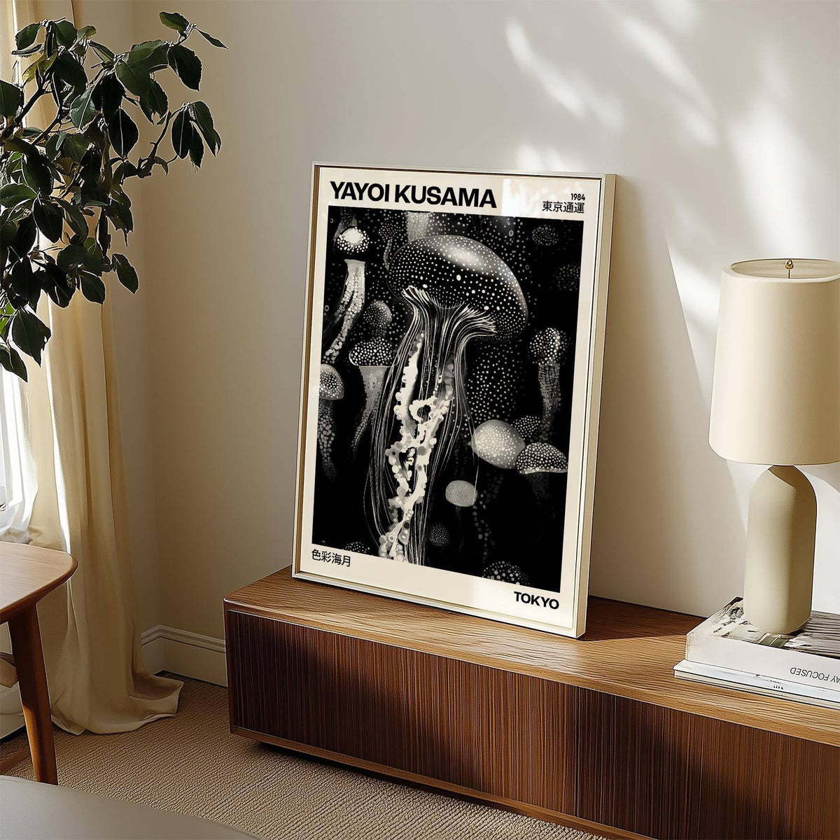 Print leaning on a sideboard of jellyfish art in black and white with a lamp and plant nearby