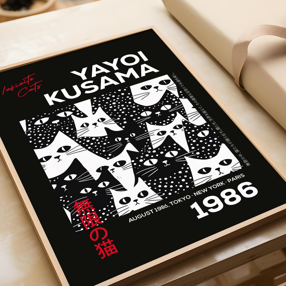 Framed Cats Black Poster with black and white minimalist cat faces and red text leaning on a wooden surface