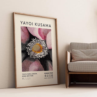 Pictures Living Room Wall leaning print of an abstract flower bloom with pink and black beside a checked sofa