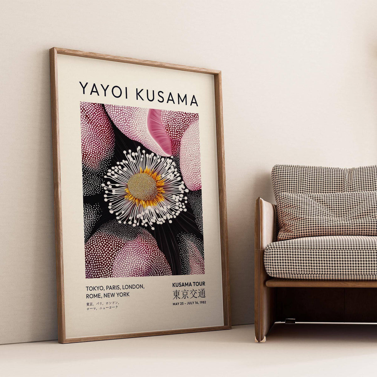 Pictures Living Room Wall leaning print of an abstract flower bloom with pink and black beside a checked sofa