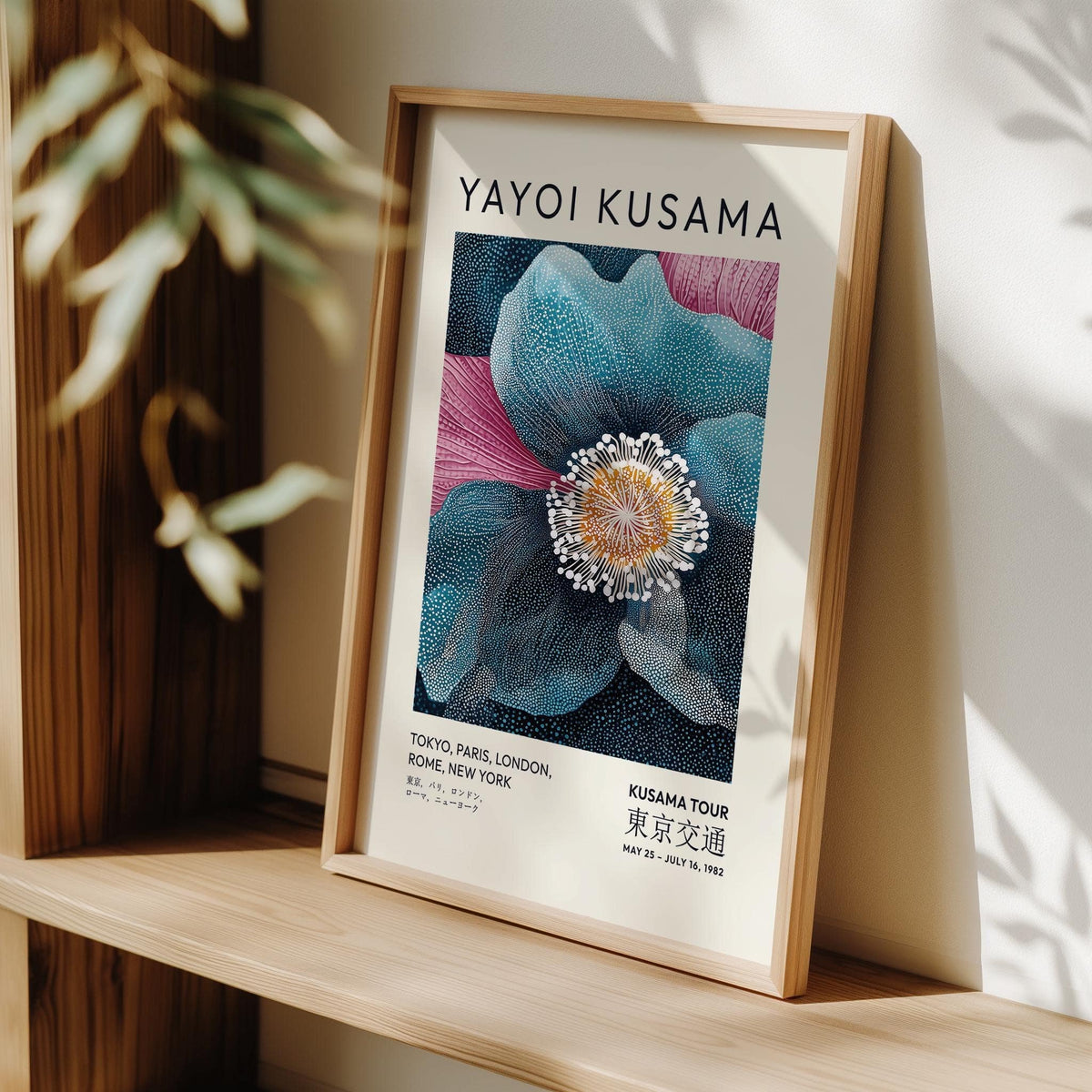 Framed close-up of blue flower artwork with orange centre on a wooden shelf with plant shadows