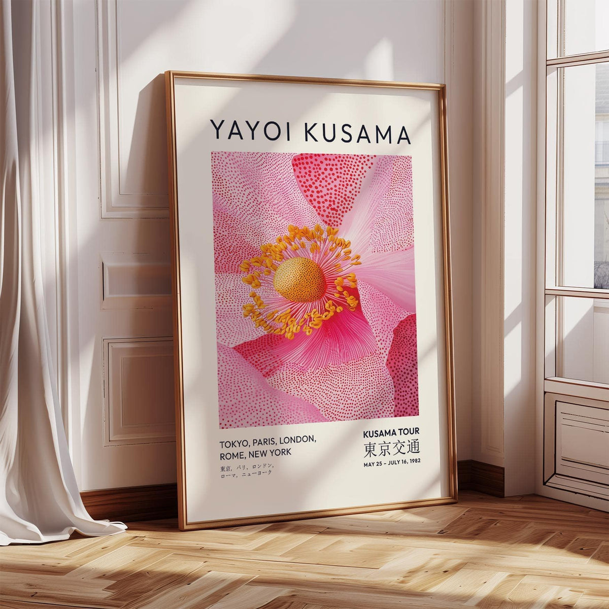Pink floral wall art leaning on a wooden floor by a window with white curtains