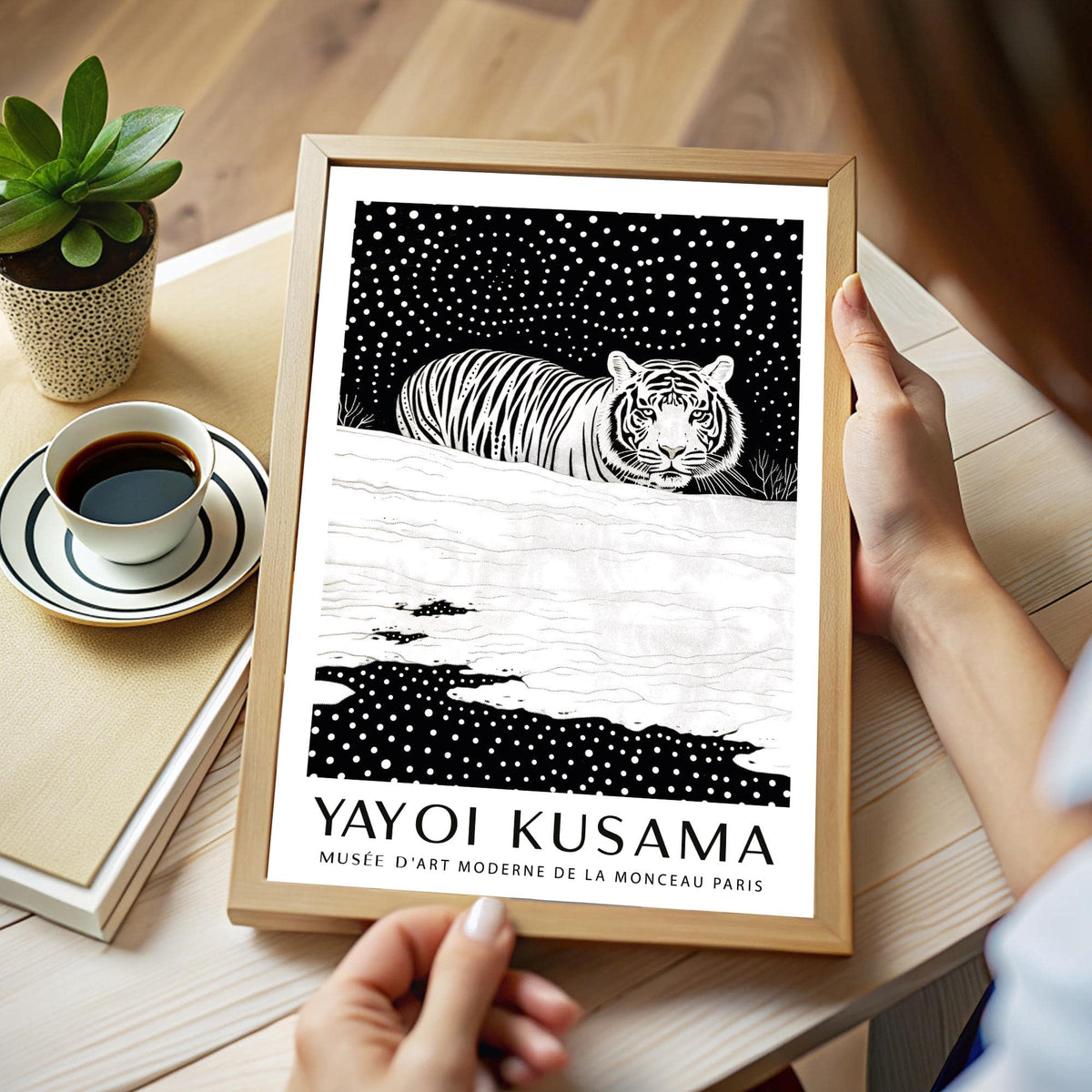Framed Snow Tiger Print with white tiger and dotted black sky held by hands next to cup of coffee