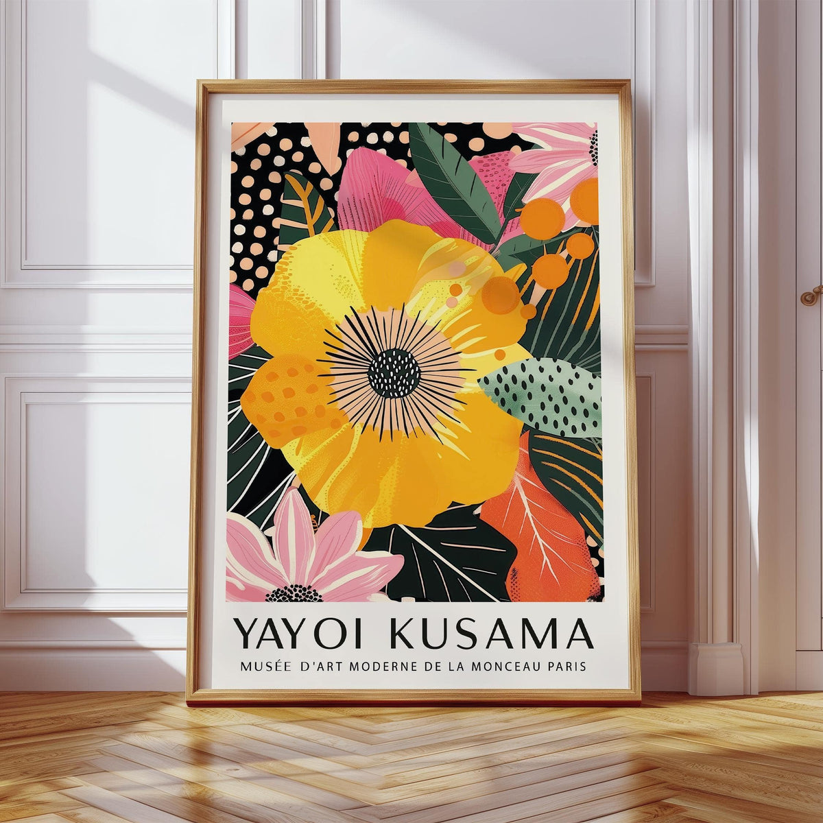 Framed print of a yellow tropical flower with pink and orange leaves leaning on a wooden floor