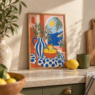 Italian Coast Print, a small A4 framed print leaning on a pale stone kitchen worktop