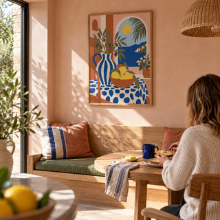 Italian Coast Print, framed on the wall of a sunny breakfast nook in a UK kitchen extension with pale peach plaster walls and a built-in oak bench