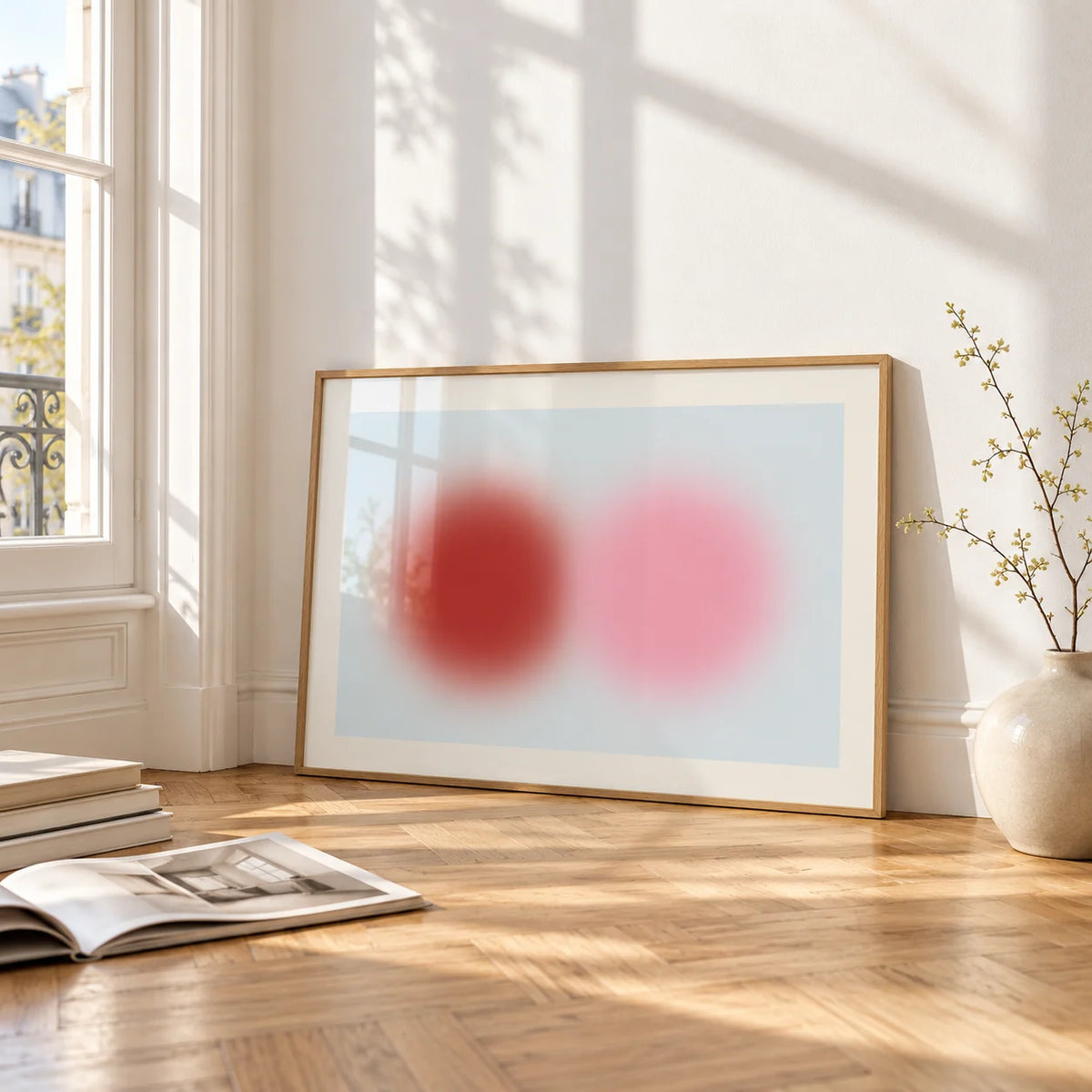 Red and Pink Circles Print, framed and leaning on the parquet floor of a bright living room