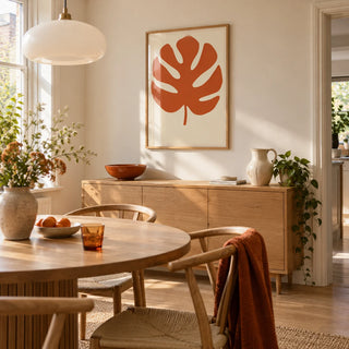 Monstera Print, framed on the wall of a bright modern dining room in a terraced house with an ivory wall and a round oak dining table with curved wooden chairs