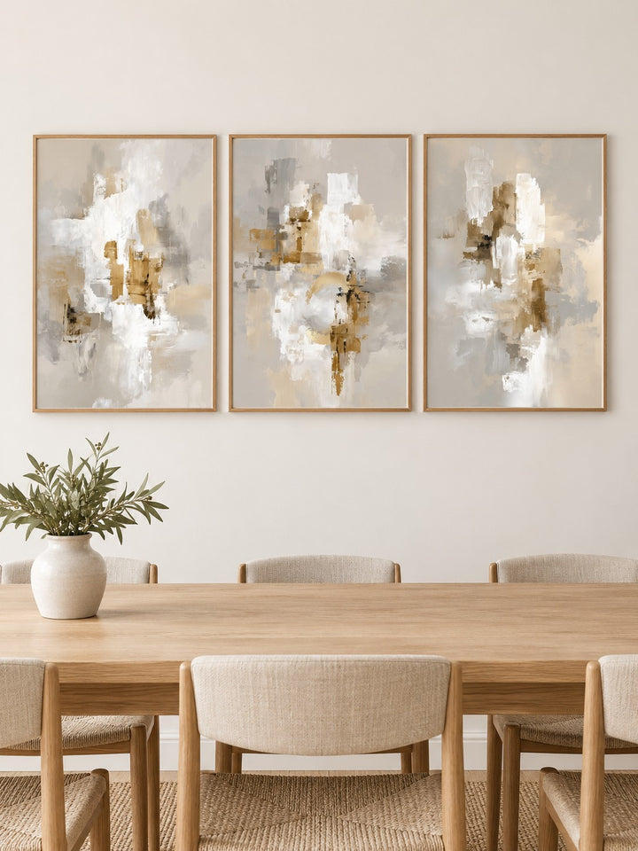 Neutral dining room wall art hung at eye level above a dining table: Neutral Brushstrokes, Modern Gold Abstract and Neutral Abstract Print shown framed side by side (frames not included)