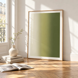Olive Green Abstract Wall Art, framed and leaning on the parquet floor of a bright living room